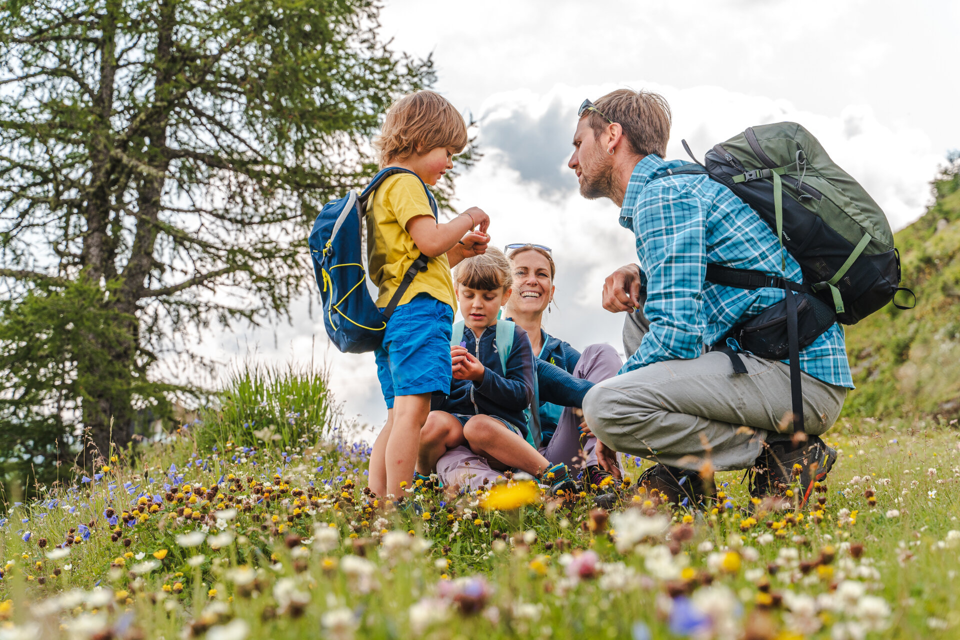 Famiglia gioca felice in un prato fiorito in Val di Fassa | © Patricia Ramirez - Archivio Immagini ApT Val di Fassa