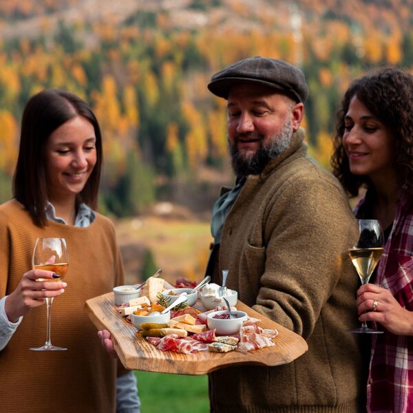 Gruppo di persone assaggia un tagliere di prodotti tipici autunnali della val di Fassa | © Archivio Immagini ApT Val di Fassa - Federico Modica 