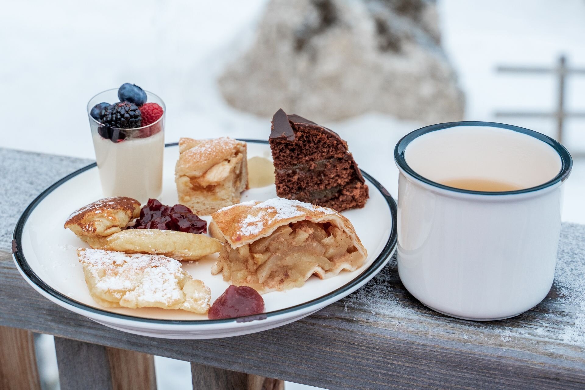 Piatto da colazione con dolci tipici trentini e tazza di caffè appoggiato sul balcone di un rifugio in inverno | © Archivio immagini ApT Val di Fassa - Patricia Ramirez