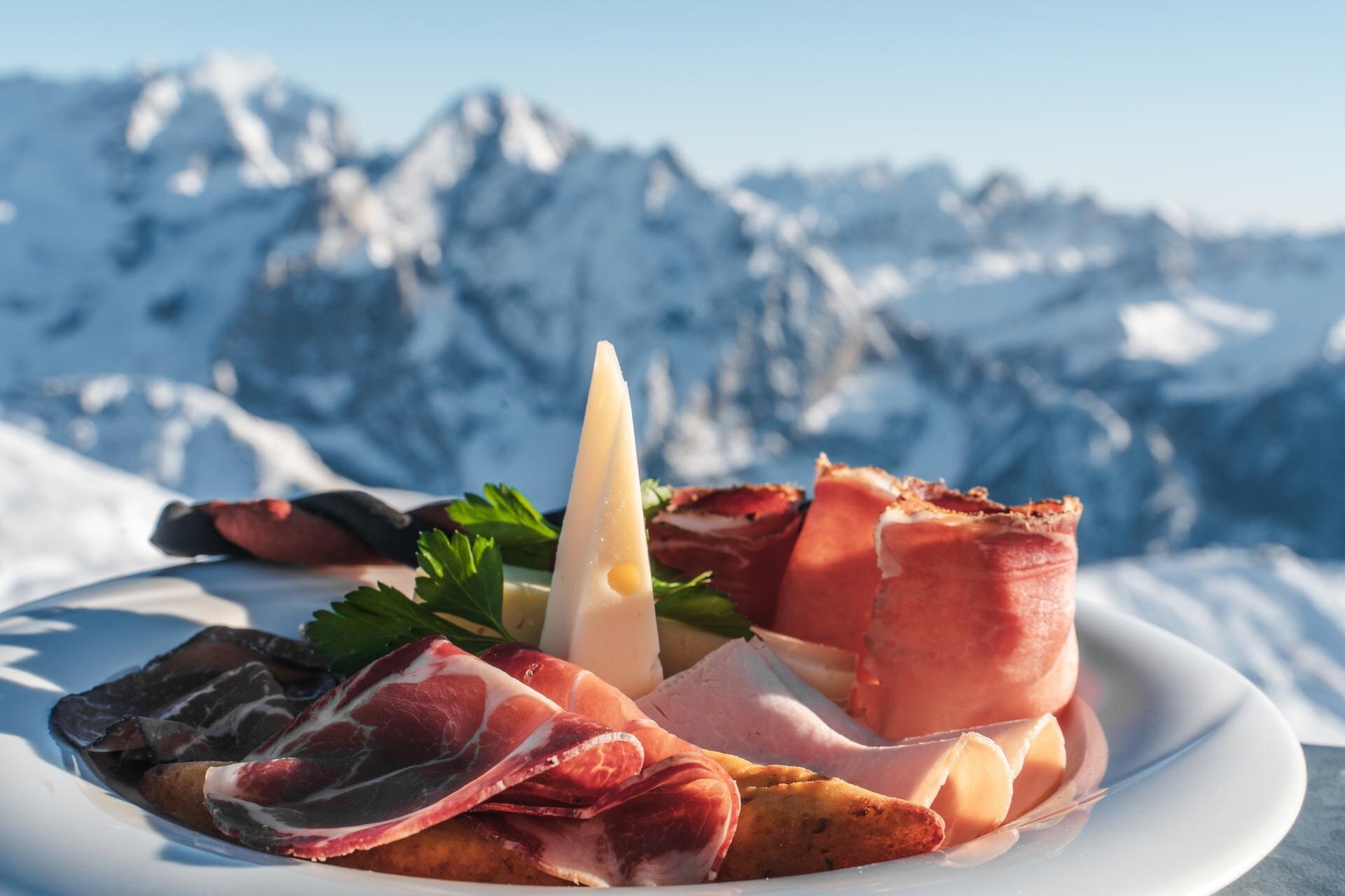 Piatto con formaggi e affettati tipici della Val di Fassa con vista sulla Marmolada | © Archivio Immagini ApT Val di Fassa - Patricia Ramirez